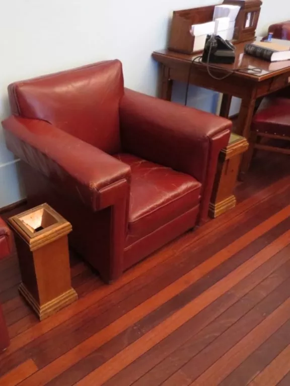 Pedestal ashtray designed in 1926, made from timber and metal. Rectangular wooden pedestal ashtray sitting between two red leather chairs.