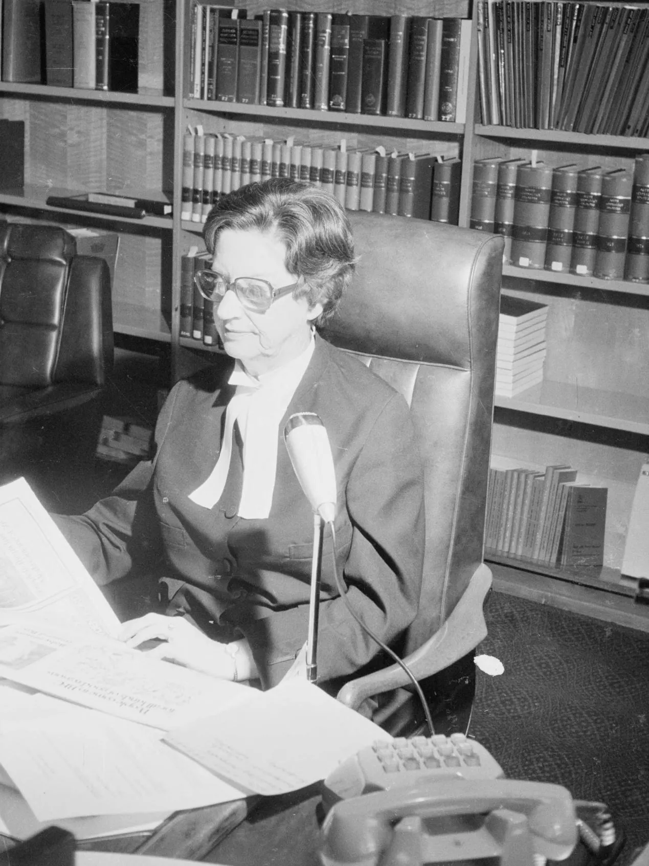 Dame Roma Mitchell, appointed Governor of South Australia in 1991, was the first woman to serve as an Australian state governor. As of 2018, every state has had at least one woman in its Government House.
Photograph National Library of Australia
A woman, Justice Roma Mitchell sits at a desk covered in papers, in front of a bookshelf filled with bound volumes.