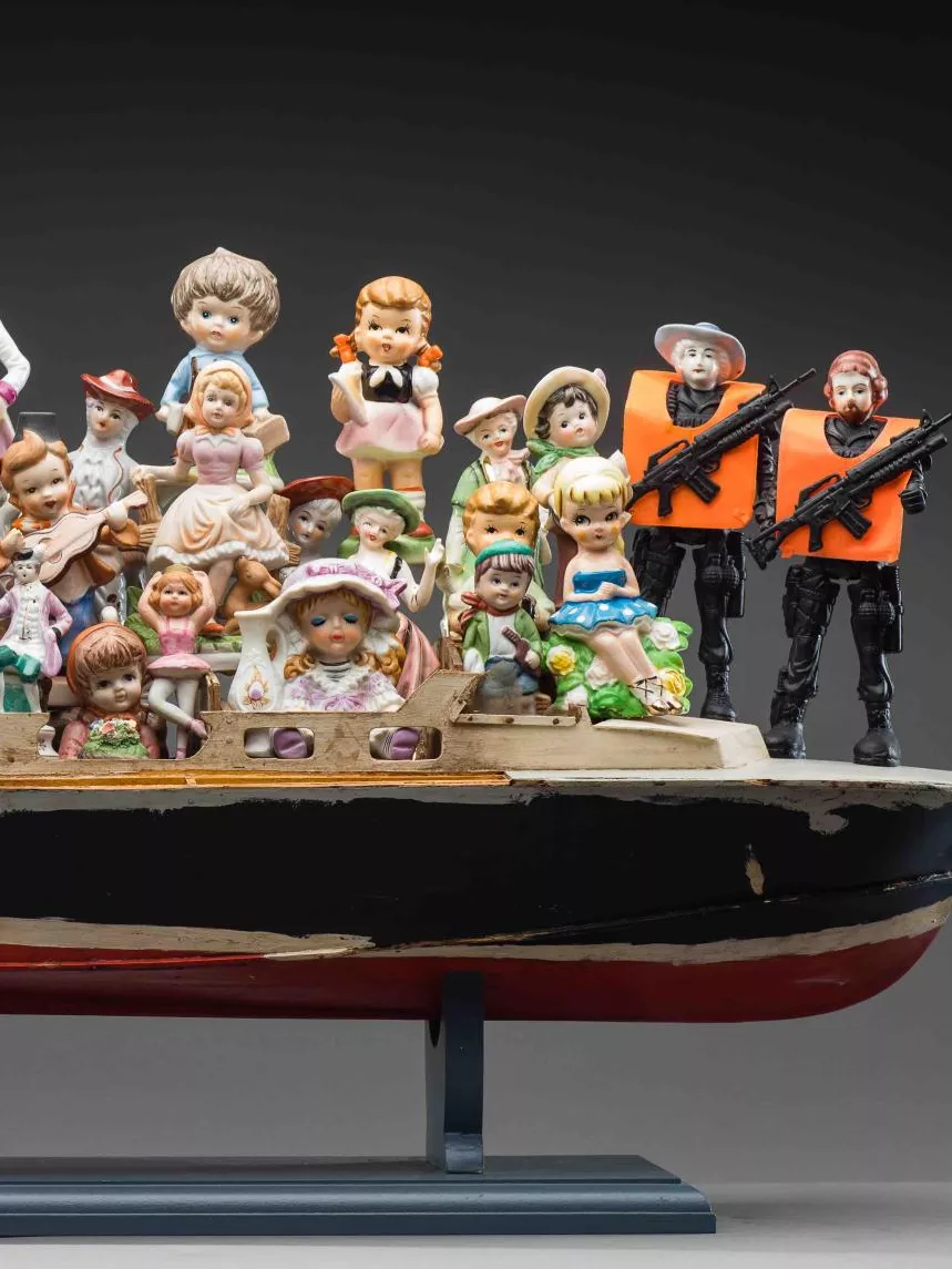 A porcelain statue of a boat filled with men, women and children in formal old fashioned outfits wearing bonnets, waist coats and bows and hats. There are 3 figurines win all black with orange vests and machine guns. A porcelain statue of a boat filled with men, women and children in formal old fashioned outfits wearing bonnets, waist coats and bows and hats. There are 3 figurines win all black with orange vests and machine guns.