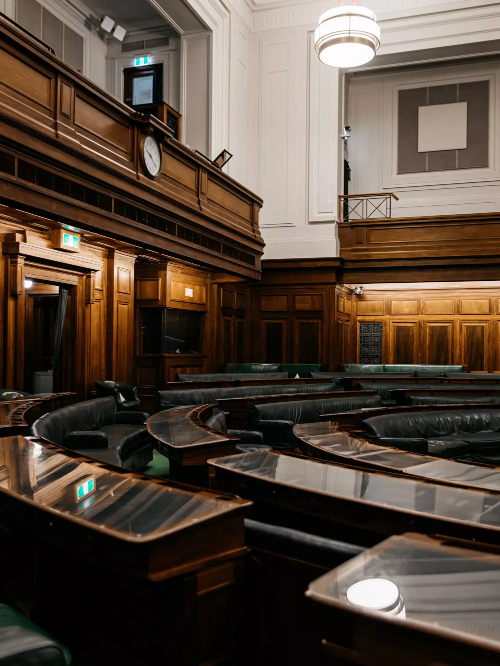 A row of desks in a U shape with green leather.
