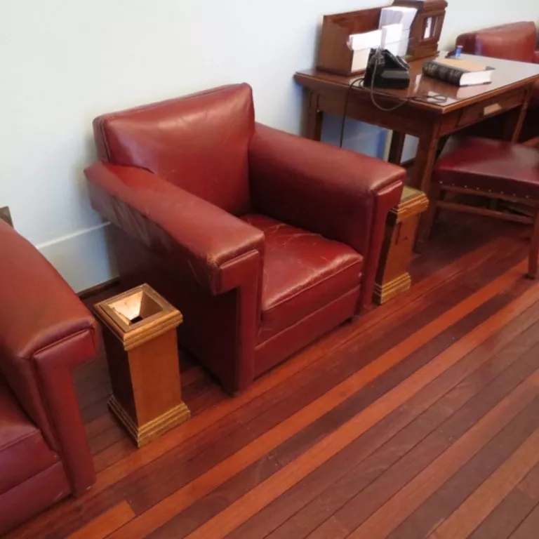 Pedestal ashtray designed in 1926, made from timber and metal. Rectangular wooden pedestal ashtray sitting between two red leather chairs.