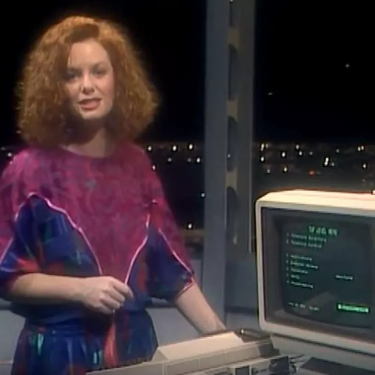Five minutes of fame on Beyond 2000 with presenter Carmel Travers. Seven Network. TV presenter Carmel Travers, wearing a blue and purple dress, demonstrating the Computerphone on 'Beyond 2000'.
