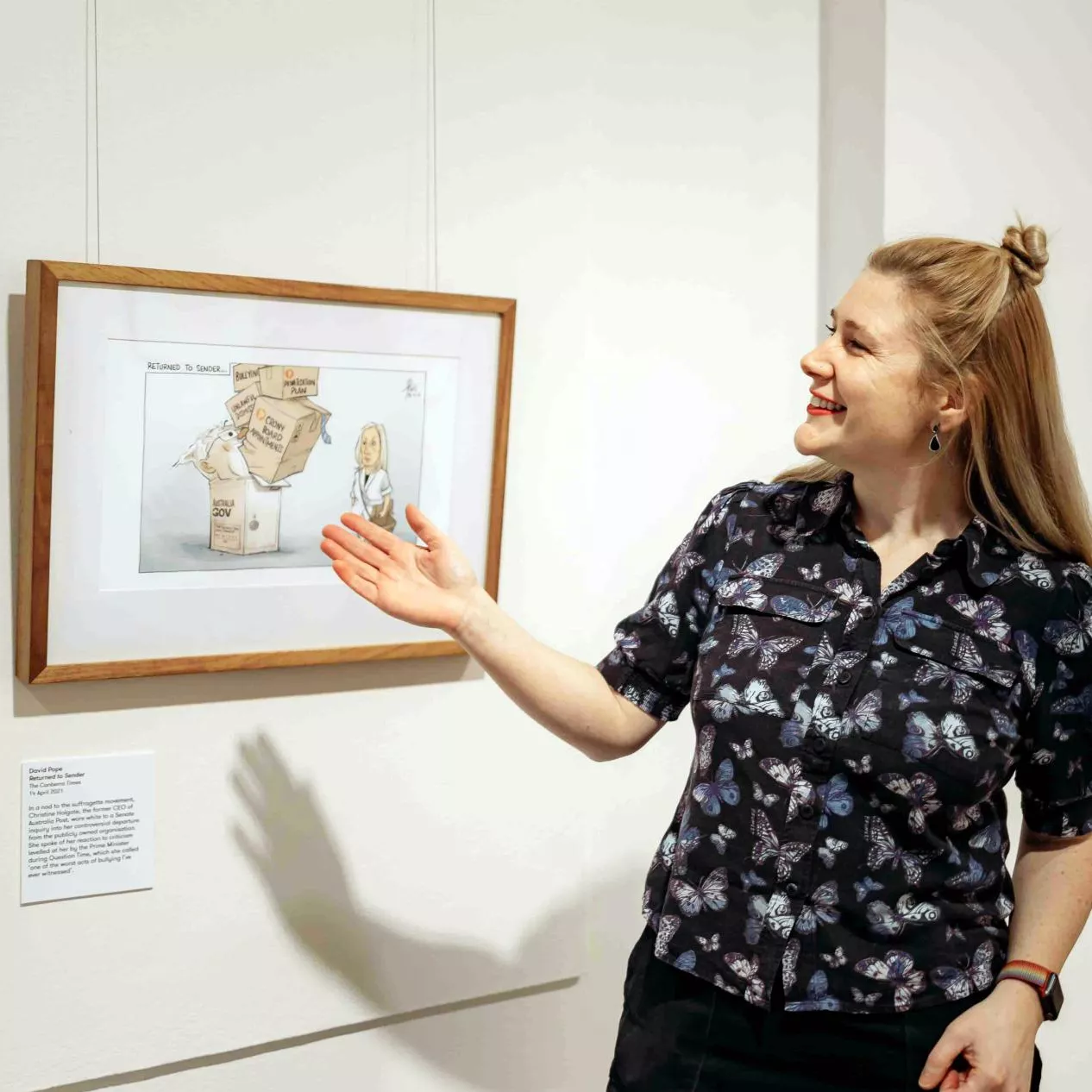 A MoAD educator stands in front of a political cartoon hanging on the wall. 
