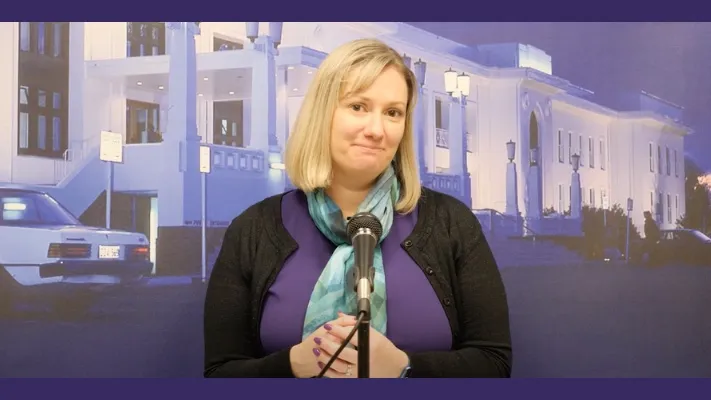A woman stands in front of a screen with an image of Old Parliament House on it. A woman stands in front of a screen with an image of Old Parliament House on it.