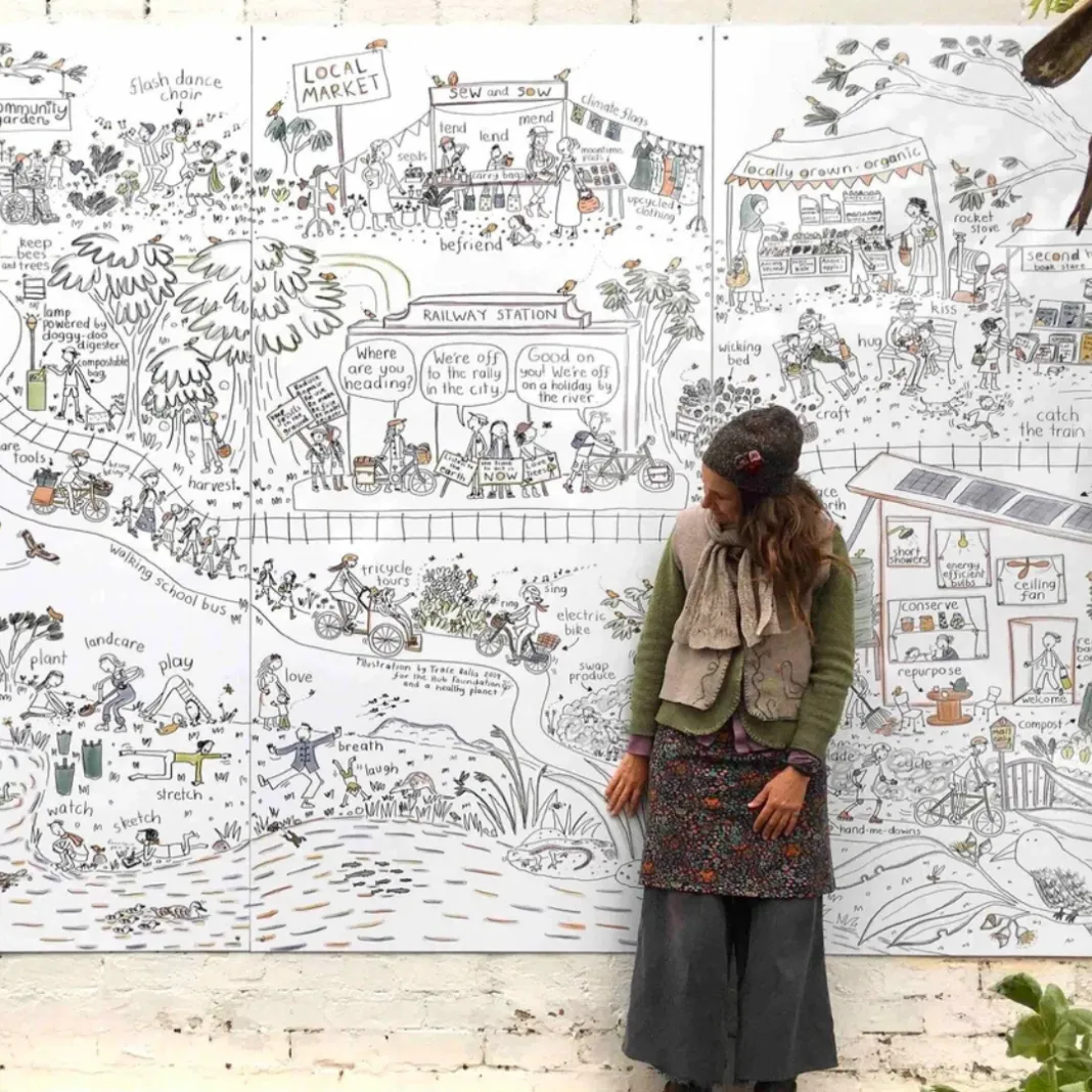 Trace Balla standing in front of a large mural illustration showing people living in nature. The mural is titled 'Live lightly for a safe climate'.