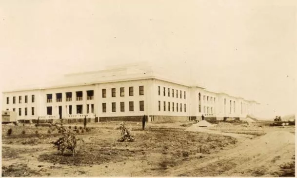 This sepia photograph depicts the undeveloped landscape around Parliament House in 1927 when the building first opened. The building sits in the centre of the image and to the left of the building are a few sad looking shrubs and the outline of the boundary of what would eventually become the House of Representatives Garden. This sepia photograph depicts the undeveloped landscape around Parliament House in 1927 when the building first opened. The building sits in the centre of the image and to the left of the building are a few sad looking shrubs and the outline of the boundary of what would eventually become the House of Representatives Garden.