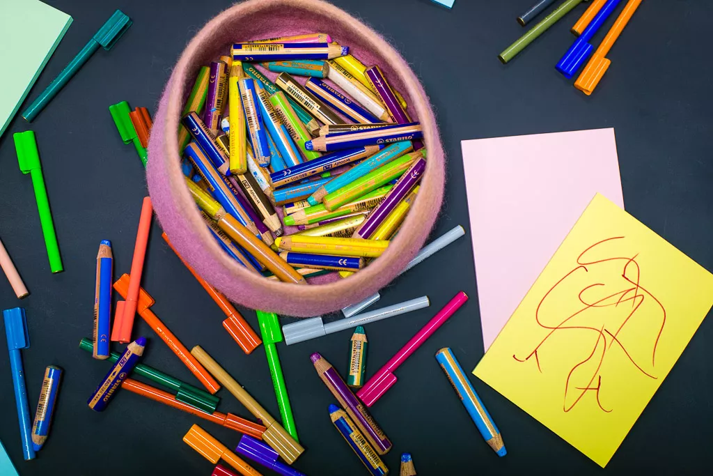 A close up of a circular felt container of pens, textas and crayons. A close up of a circular felt container of pens, textas and crayons.