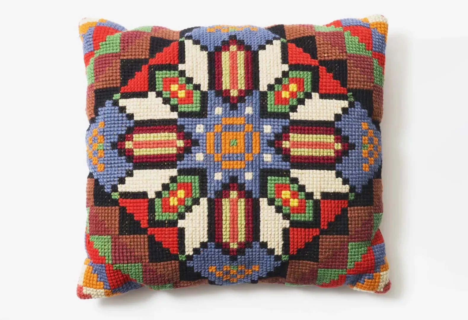 A square embroidered cushion with a geometric pattern using green, yellow, red, blue, orange, black and white threads. A square embroidered cushion with a geometric pattern using green, yellow, red, blue, orange, black and white threads.
