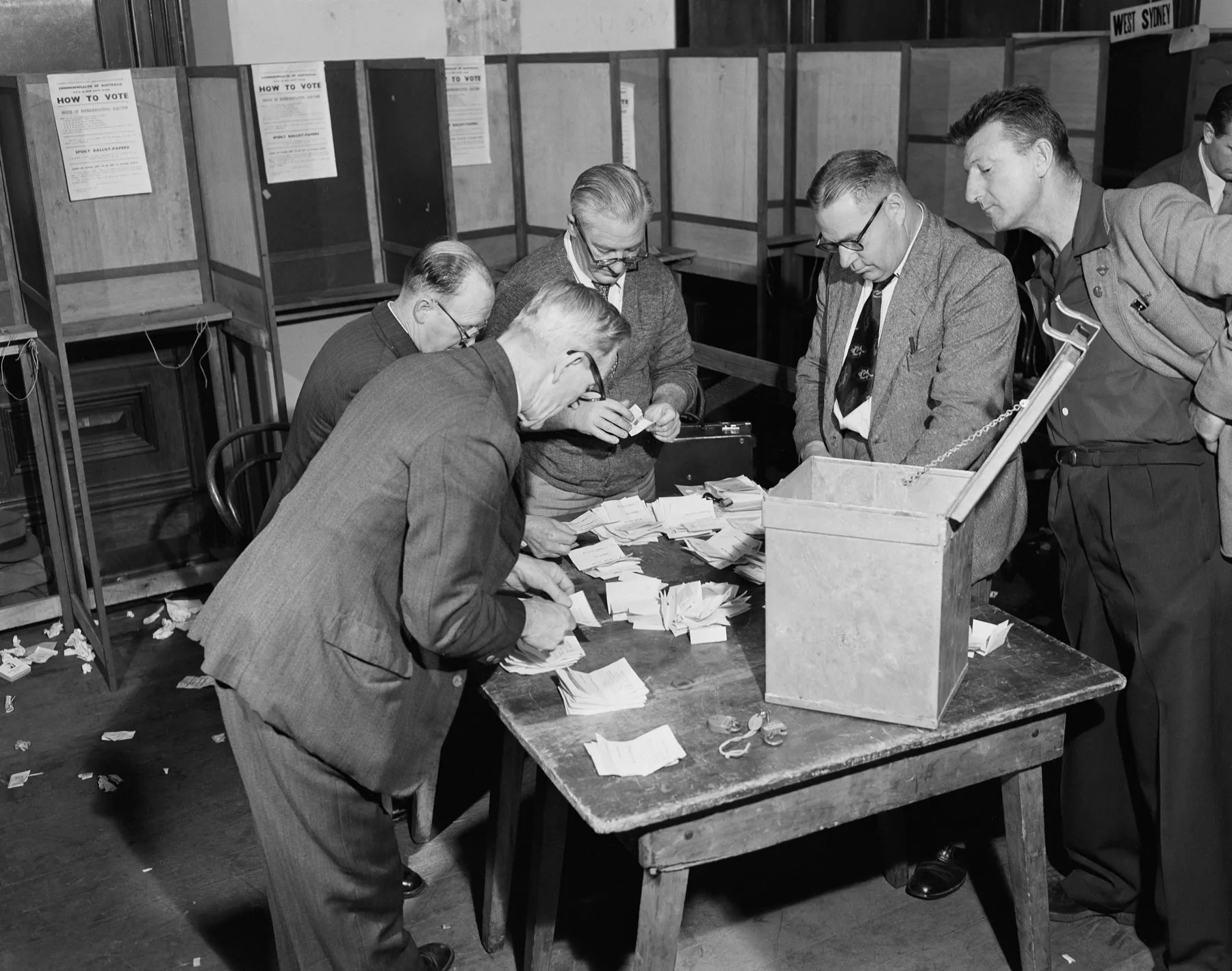 Men in suits count votes on a table in the Sydney Tally Room during the 1954 federal election. Men in suits count votes on a table in the Sydney Tally Room during the 1954 federal election.